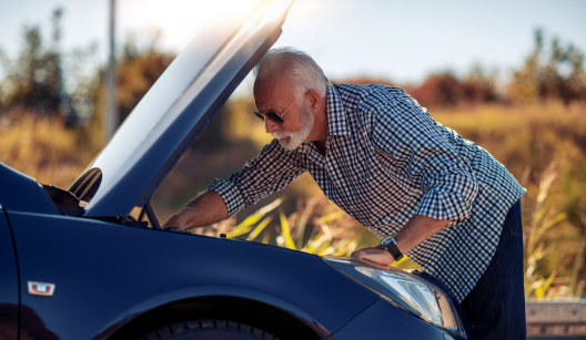 Man Looking Under The Hood Of His Broken Down Luxury Vehicle